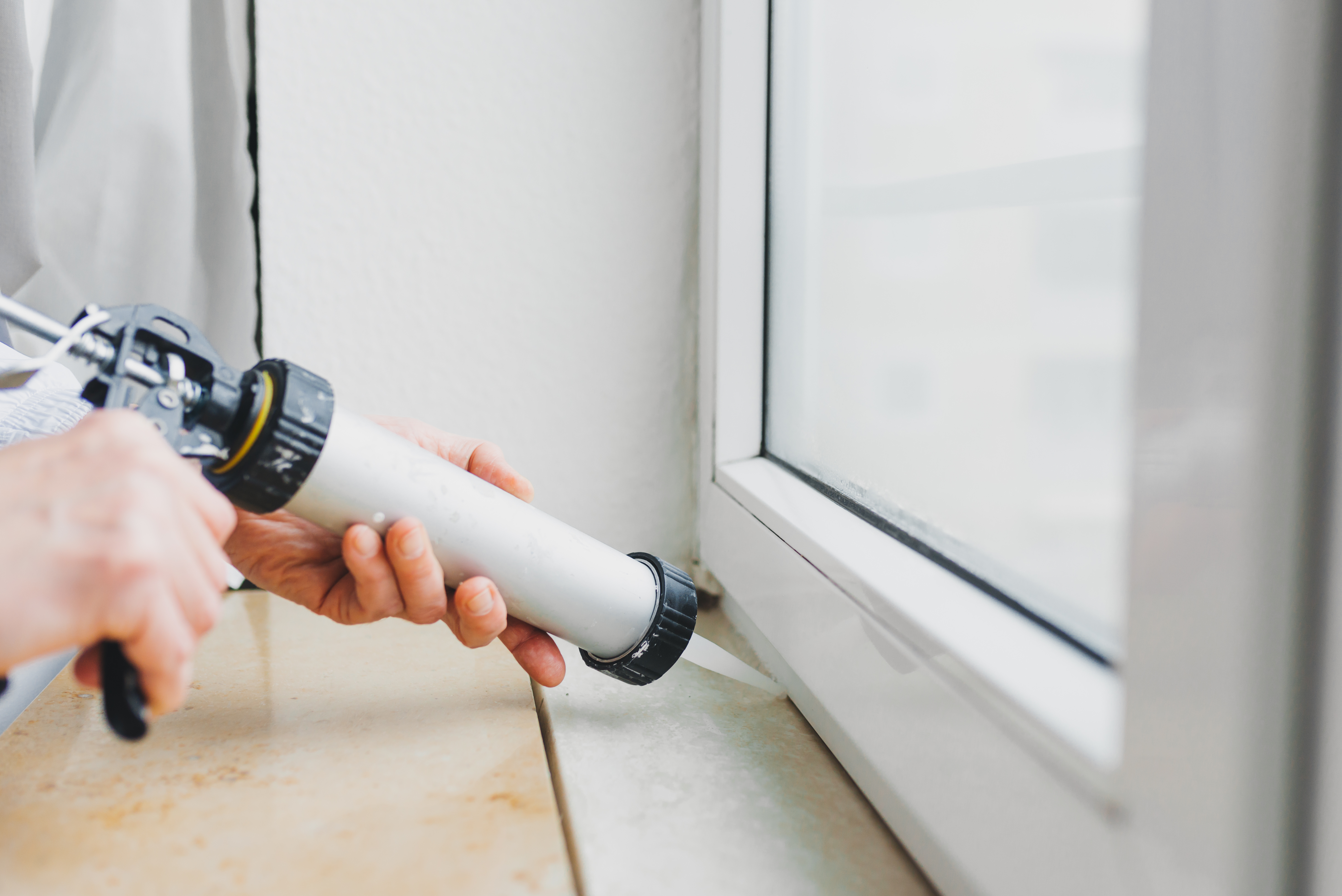Professional air sealing a window frame with caulk gun